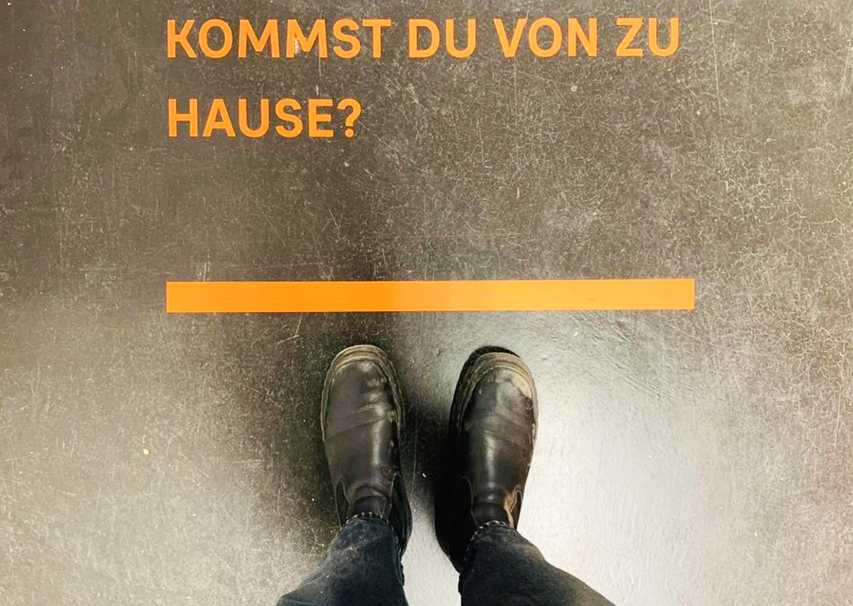 zwei Füße vor dem Spruch: Kommst du von zu Hause?