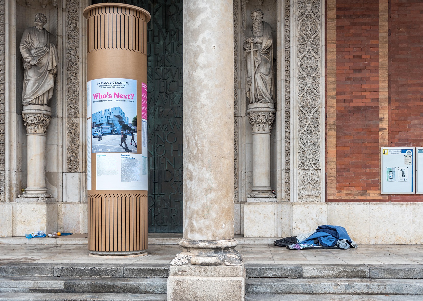 poster on column, column and homeless lying on the floor 